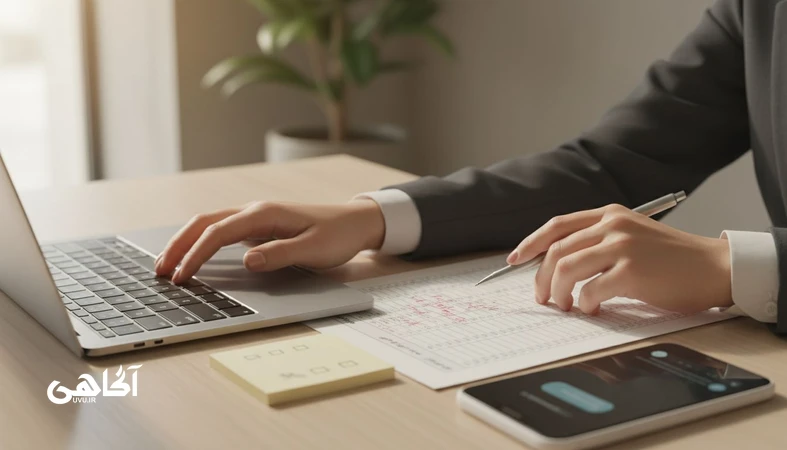 تعارض ارزش ها در کار در یک میز اداری ایرانی؛ دست ها کنار گزارش و لپ تاپ در لحظه درنگ و تصمیم گیری اخلاقی، مجله آگاهی